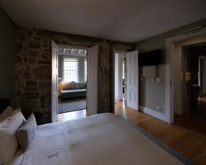 une chambre avec un grand lit blanc dans une pièce dans l'établissement Casa do Juncal, à Guimarães
