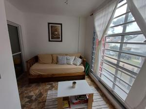 a living room with a couch and a large window at Depto Costa in San Bernardo