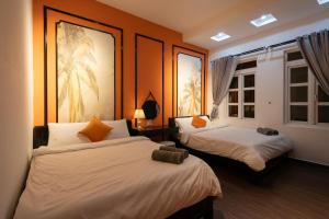 two beds in a room with orange walls and windows at Elva Shine Dalat Hotel in Da Lat