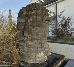 une statue en pierre d'une tête devant une maison dans l'établissement BUDA Lodge 6-4, à Oberhausbergen