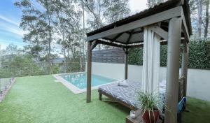 een prieel met een bed en een zwembad bij Wild Edge Retreat in Wollombi +7 foto's