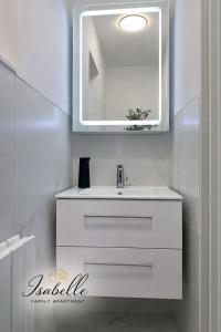 ein Badezimmer mit einem weißen Waschbecken und einem Spiegel in der Unterkunft Isabelle Family Apartment Nähe Schloss Dankern in Haren