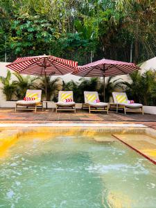 a pool with two umbrellas and lounge chairs at Ombligo Connection House in Valle de Bravo