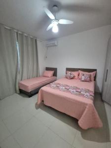 een slaapkamer met twee bedden en een plafondventilator bij Elis Praia e Aconchego in Iguaba Grande