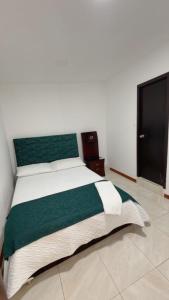 a bedroom with a large bed with a green headboard at Hotel Hierbabuena y Restaurante in Pasto