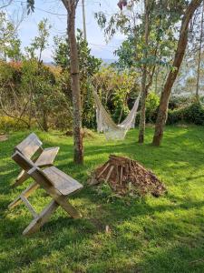 a wooden bench sitting in the grass next to a hammock at Cabaña Privada Pachamama Ancestral in Medellín