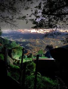 a view of a city from a hill with a fence at Cabaña Privada Pachamama Ancestral in Medellín +2 photos