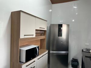 a kitchen with a microwave and a refrigerator at Chalés Brisa Do Mar in São Sebastião