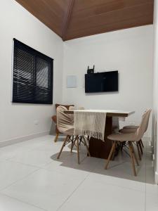 a living room with a table and chairs and a television at Chalés Brisa Do Mar in São Sebastião