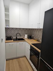 una cucina con mobili bianchi e un frigorifero nero di Apartament Dobra Nocka 2 a Przeworsk