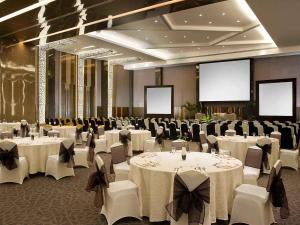 Un salón de banquetes con mesas y sillas blancas y biombos. en Novotel Bangka Hotel & Convention Center, en Pangkalpinang 103 fotos más