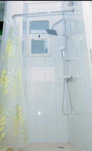 a white bathroom with a shower with a window at Charming apartment limete 1ere rue Kinshasa in Kinshasa +14 photos