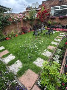 een tuin met bankjes in het gras en bloemen bij One Bedroom Flat in London Heathrow 20 minutes drive in Greenford