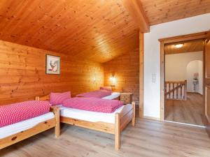 two beds in a room with wooden walls at Almruhe Alpbach in Alpbach