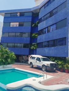 a white suv parked in front of a blue building at Suites Menavi in Acapulco