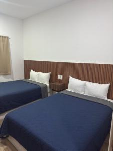 two beds in a hotel room with blue sheets at Hotel Mochomos Huajuapan in Huajuapan de León