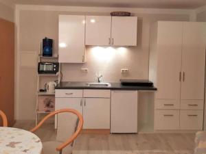 eine Küche mit weißen Schränken und einem Waschbecken und einem Tisch in der Unterkunft Holiday apartment in Parlow with parking in Parlow-Glambeck