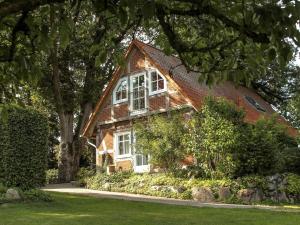 een stenen huis met witte ramen en bomen bij Romantic half-timbered house in Egestorf