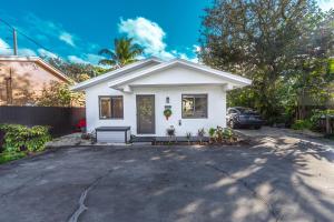 ein weißes Haus mit einem Auto, das in einer Einfahrt parkt in der Unterkunft Centrally Located Modern 2bdr Home w Fast WiFi & Parking in Miami