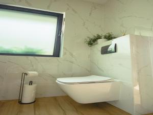 a white bathroom with a toilet and a window at A comfortable house in Kashubia for 5 people in Gołubie +25 photos