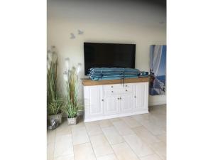 een woonkamer met een televisie op een witte kast bij House 4seasons Scharbeutz in Scharbeutz