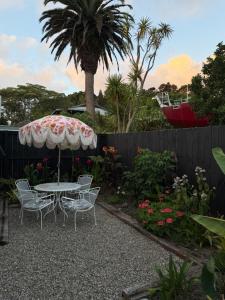 een tafel en stoelen met een parasol in de tuin bij The Hut in Russell