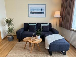 un salon avec un canapé bleu et une table dans l'établissement North Beach Pearl 2, à Norderney