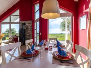 ein Esszimmer mit roten Wänden und einem Tisch mit Weingläsern in der Unterkunft Seepark - Holiday Home - Rügen in Vaschvitz