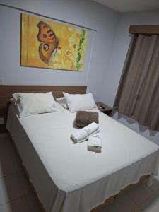een bed met twee handdoeken en een afbeelding van een vlinder bij Apartamento por Temporada Veredas Flat - Rio Quente Goias in Rio Quente