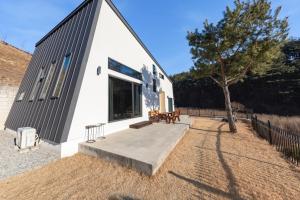 a small white building with a tree in front of it at Gangneung Solol Pension in Gangneung