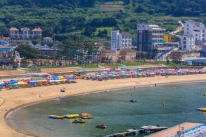 a beach with a bunch of umbrellas and a crowd of people at Geoje Haneul Ari Pension in Geoje