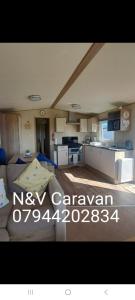een woonkamer met een bank en een keuken bij N & V Caravan Sand le mere in Tunstall +3 foto's