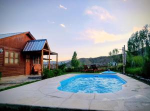 a pool in the backyard of a house with a cabin at Cabañas Rowal Malbec Potrerillos in Potrerillos