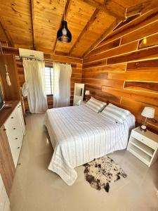 a bedroom with a bed and a wooden wall at Cabaña para 6 personas en Calamuchita - Córdoba - "La Concepción" in Embalse Rio Tercero
