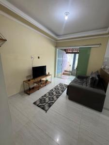 ein Wohnzimmer mit einem schwarzen Sofa und einem TV in der Unterkunft Casa da lagoa in São Pedro da Aldeia + 3 Fotos