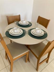a dining room table with plates and cups and chairs at Flat aconchego PNz in Petrolina