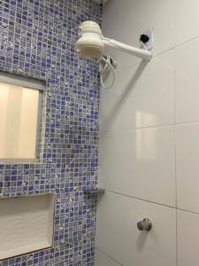 a bathroom with a shower with a mirror and blue tiles at Flat aconchego PNz in Petrolina +13 photos