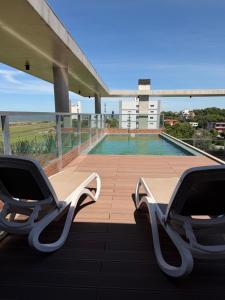 two chairs sitting on a balcony next to a swimming pool at Bello departamento en Encarnación de 2 Habitaciones con Parking! in Encarnación