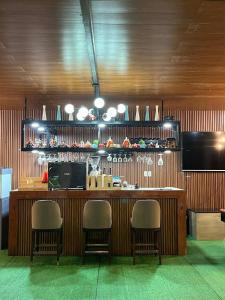 LuksuhinD LUXE Garden Resort的餐厅里的一个酒吧,周围摆放着三把椅子