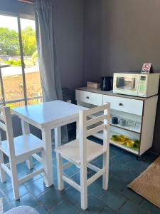 een keuken met een tafel en 2 stoelen en een magnetron bij Monoambiente Noah 2 in Ezeiza