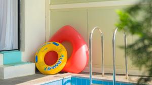 une piscine avec une bouée de sauvetage jaune et rouge à côté d'une piscine dans l'établissement Namhae Ourpoolvilla, à Namhae