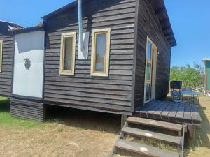 ein kleines Haus mit einer Holzterrasse und einer Treppe in der Unterkunft La viuda del diablo cabañas in Punta Del Diablo