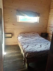 ein Schlafzimmer mit einem Bett in einer Holzhütte in der Unterkunft La viuda del diablo cabañas in Punta Del Diablo