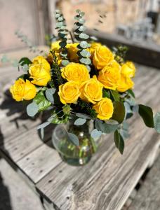 BatesvilleThe Royal on Main的木桌上放着一瓶插满黄玫瑰的花瓶。