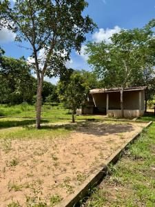 a building in the middle of a field with a tree at Pousada e Camping São José in Manhã