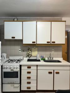 a kitchen with white cabinets and a stove and a sink at Espacio necochea in Mendoza +7 photos
