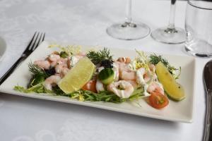 een witte plaat met garnalen en groenten op een tafel bij Helnan Phønix Hotel in Aalborg