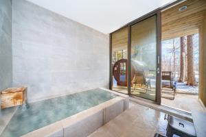 una grande vasca in una stanza con una grande finestra di Noah Rusutsu a Rusutsu