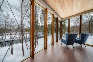 una stanza con finestre di vetro e sedie blu nella neve di Noah Rusutsu a Rusutsu