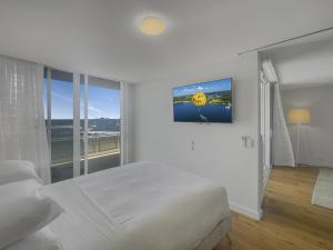 ein weißes Schlafzimmer mit einem Bett und einem großen Fenster in der Unterkunft Spacious Modern Apartment in Batemans Bay in Batemans Bay